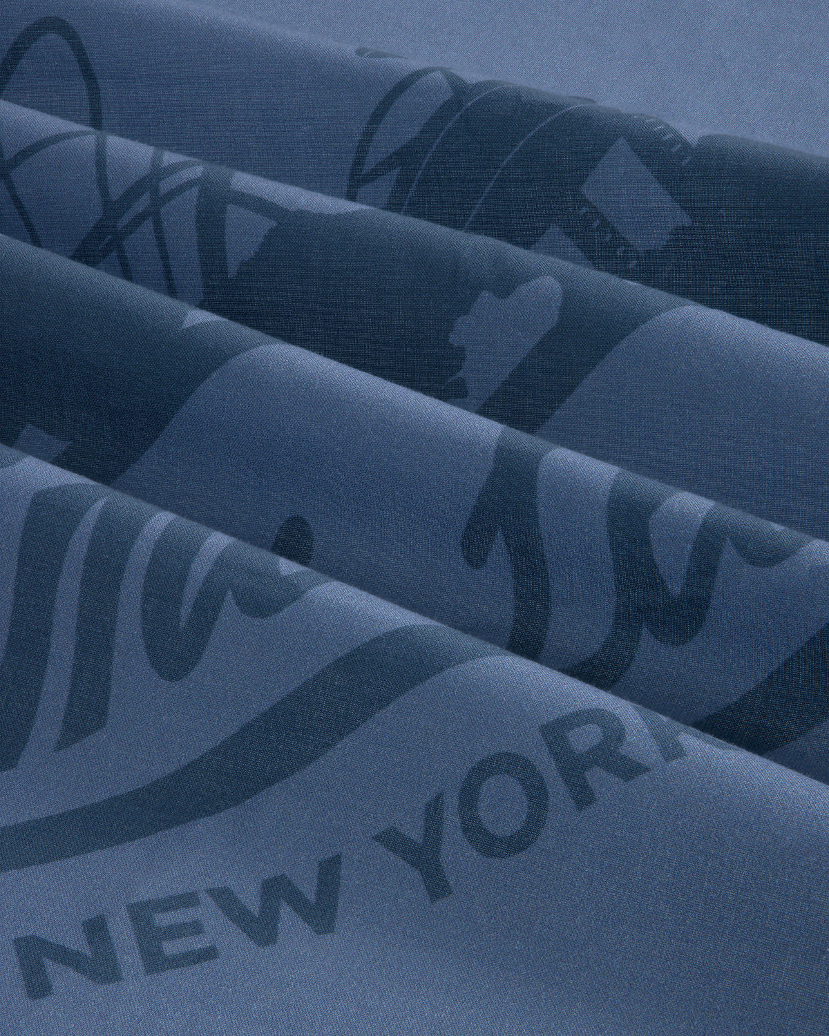 Close-up of blue Sun Faded Unisphere Bandana with partially visible printed text and graphics, including New York.
