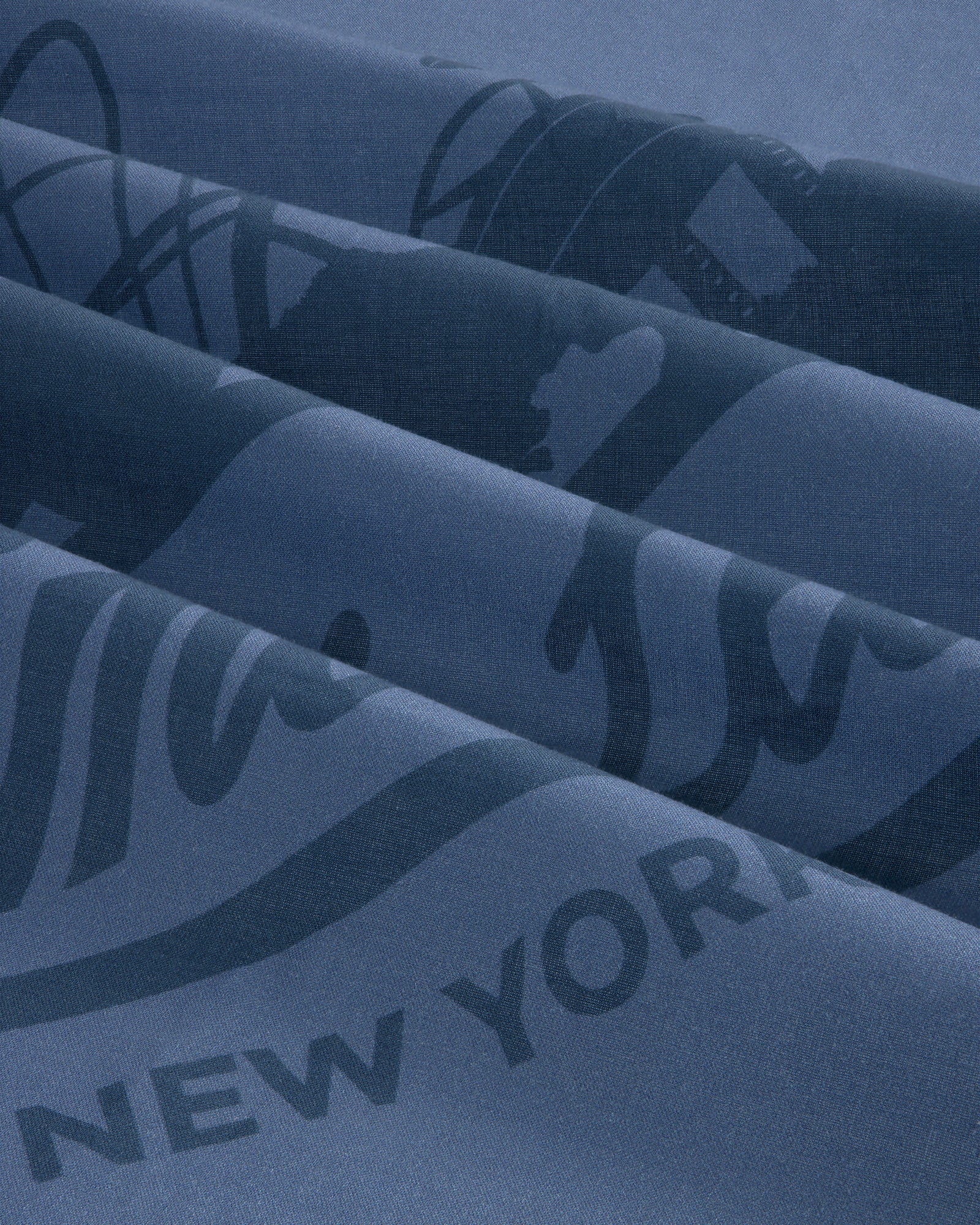 Close-up of blue Sun Faded Unisphere Bandana with partially visible printed text and graphics, including New York.