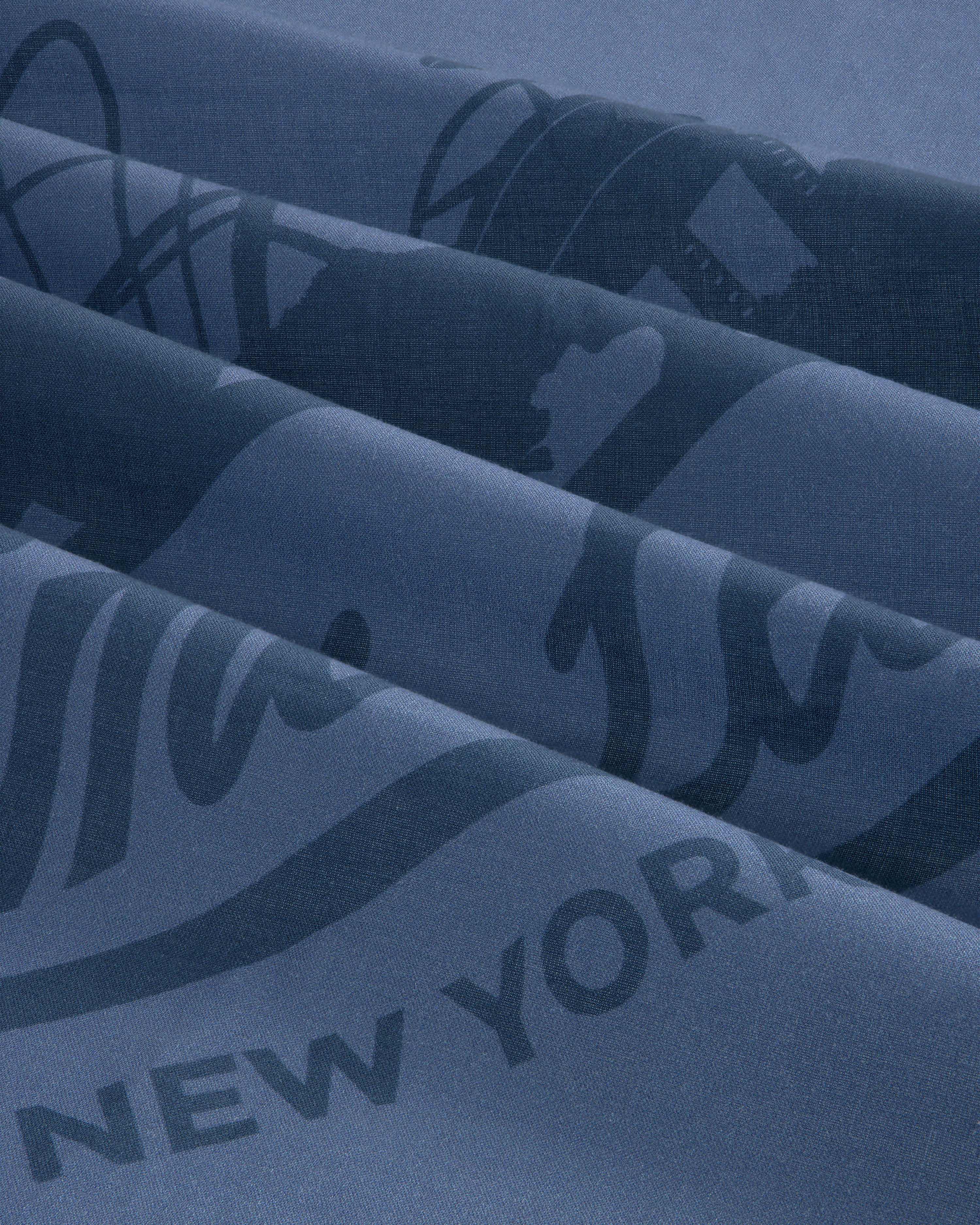 Close-up of blue Sun Faded Unisphere Bandana with partially visible printed text and graphics, including New York.