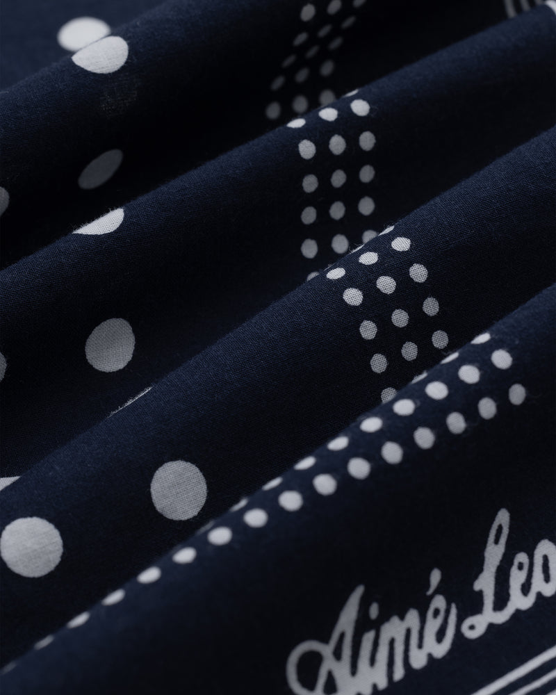 Polka Dot Bandana in navy blue with white polka dots and cursive Aimé Leon text, shown in folded layers.