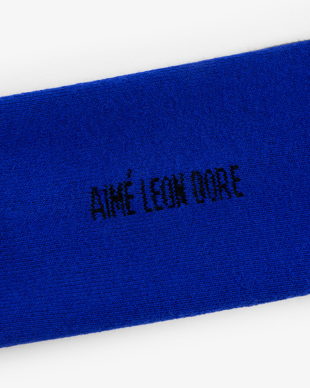 Close-up of blue fabric with black AIMÉ LEON DORE embroidery from the Crew Sock 3-Pack.