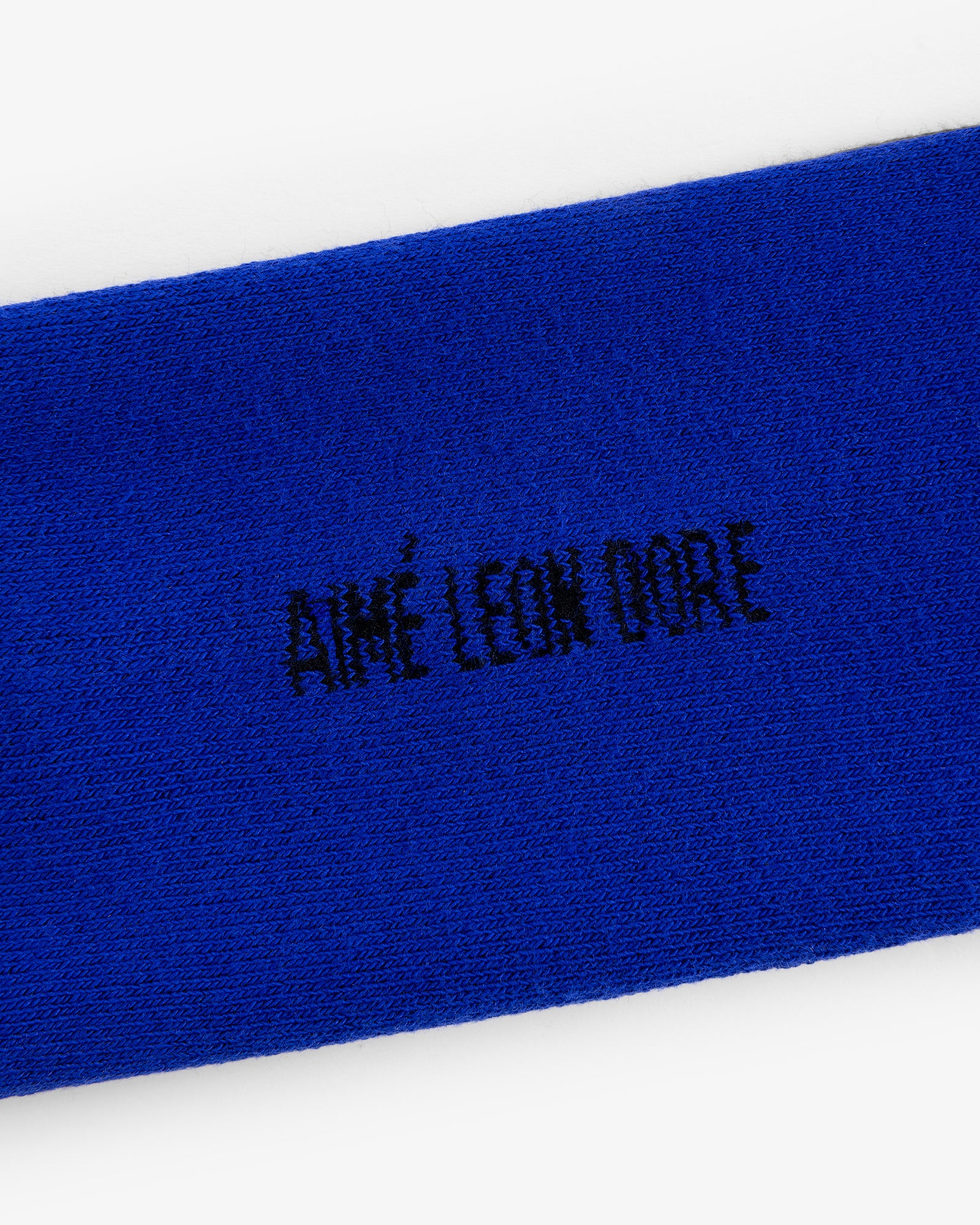 Close-up of blue fabric with black AIMÉ LEON DORE embroidery from the Crew Sock 3-Pack.