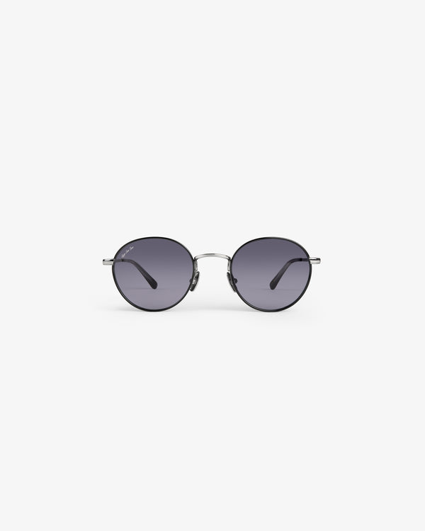 Giórgios Sunglasses: round black frames, dark lenses, and a thin silver bridge on a plain white background.