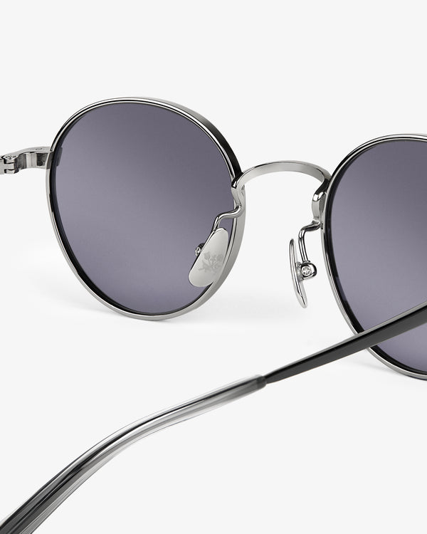 Close-up of Giórgios Sunglasses with dark lenses and silver metal frames on a white background.