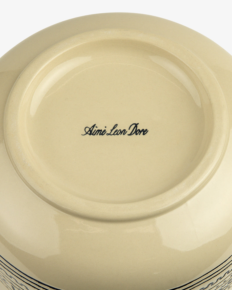 The underside of a beige Textile Patterned Treat Jar with Aimé Leon Dore in black script at the center.