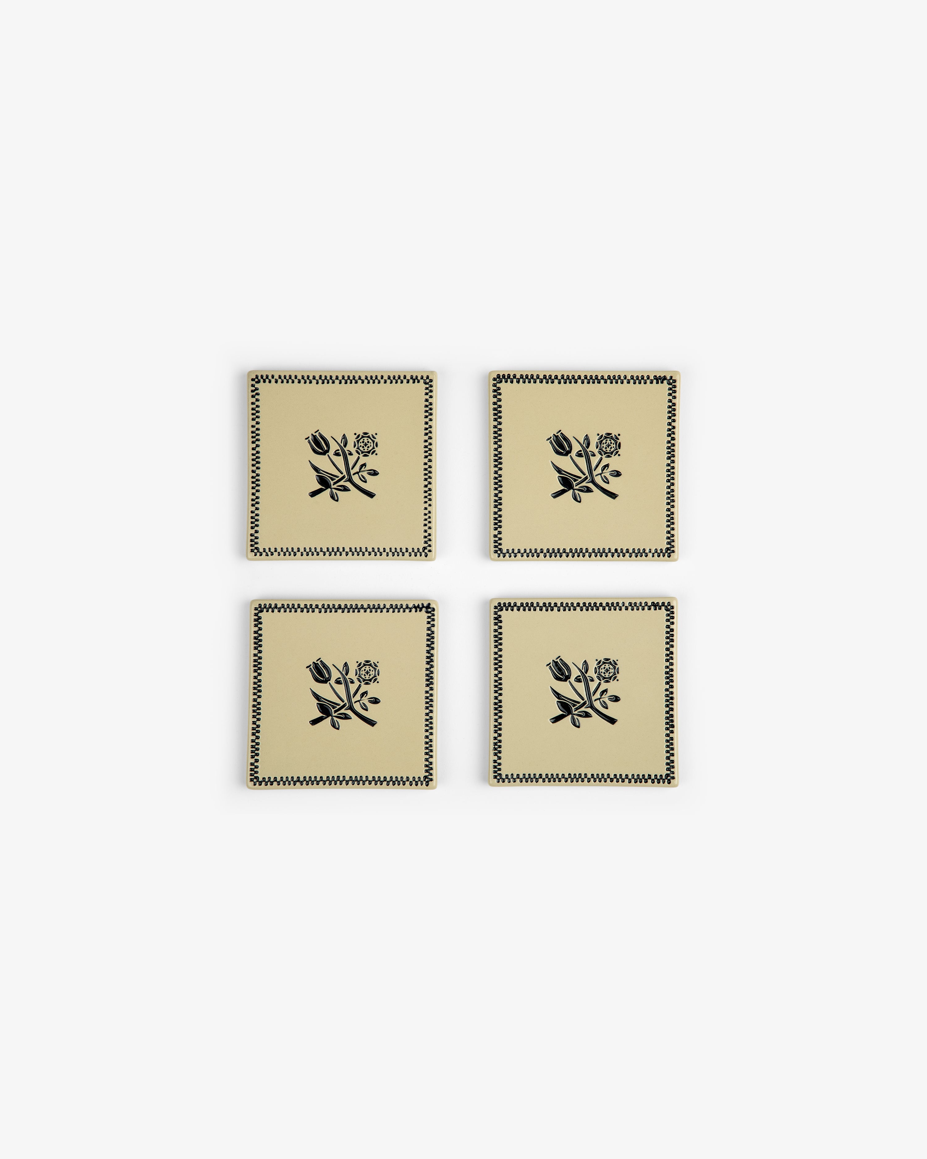 Crest Coaster (Set of 4): Beige coasters with black floral and zigzag designs, arranged in a two-by-two grid.