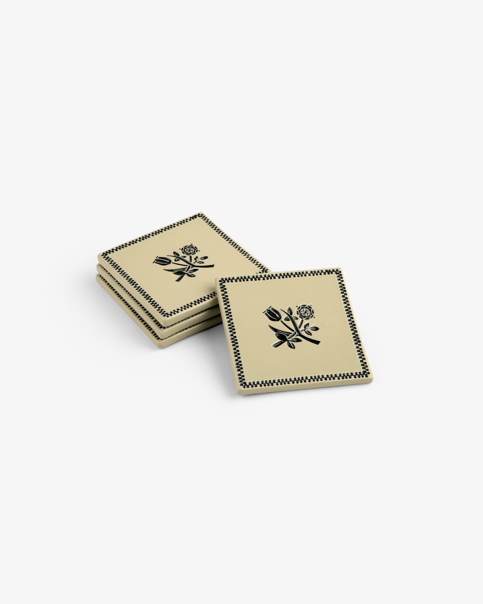 Set of 4 Crest Coasters with black floral design, stacked in two piles on a white background.