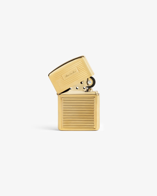 Brass Zippo Lighter with ribbed texture, open lid, and engraved script on top, set against a white background.
