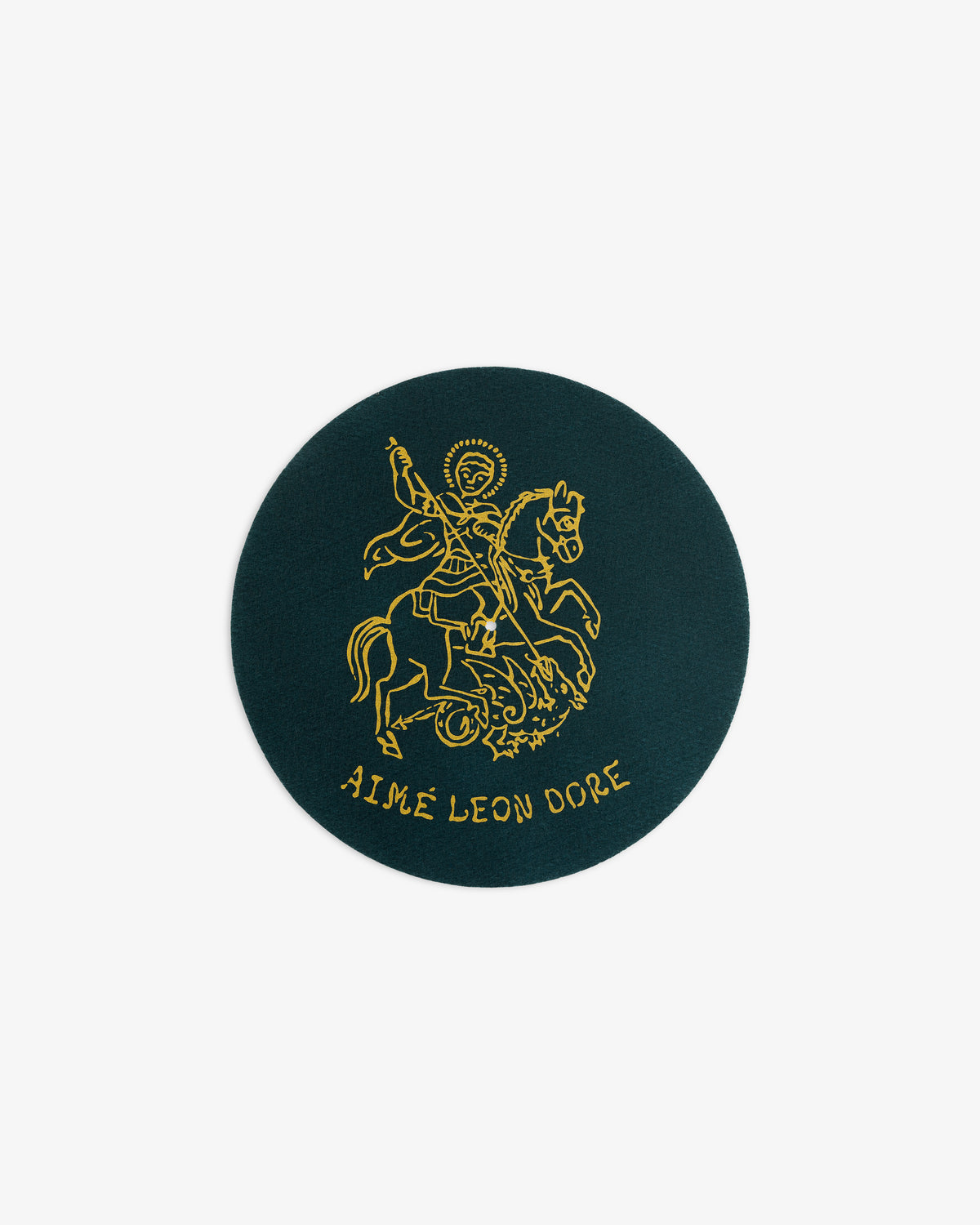 A round dark green patch from Graphic Slip Mats with a gold line drawing of a rider and AIMÉ LEON DORE below.
