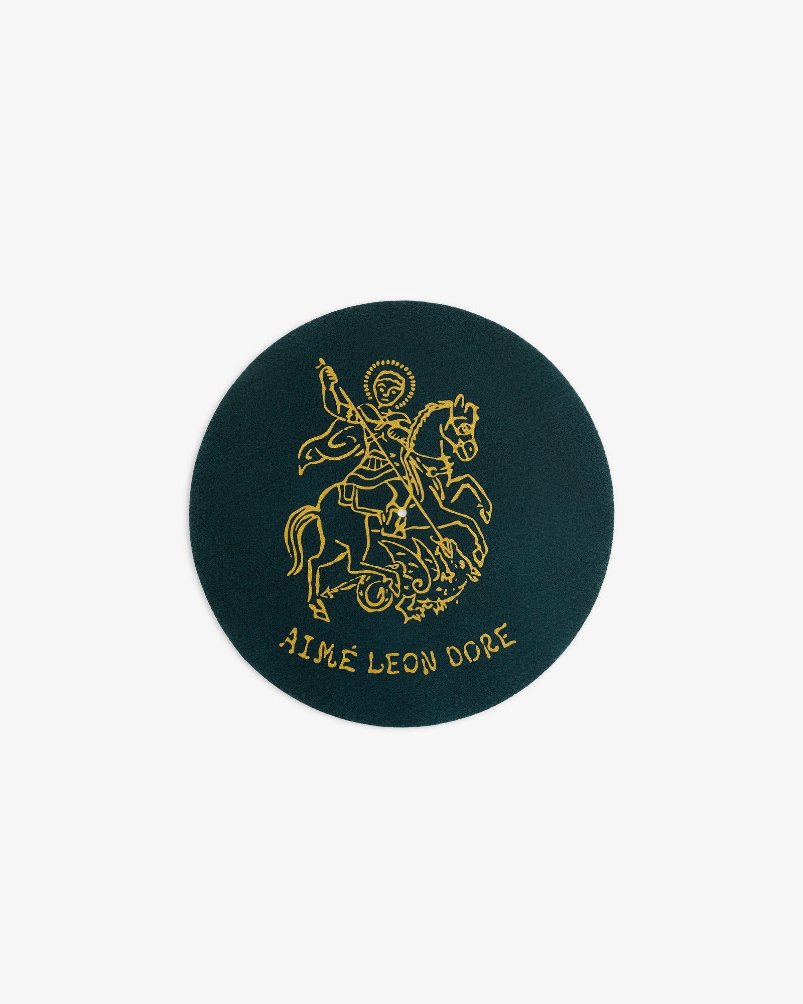 A round dark green patch from Graphic Slip Mats with a gold line drawing of a rider and AIMÉ LEON DORE below.