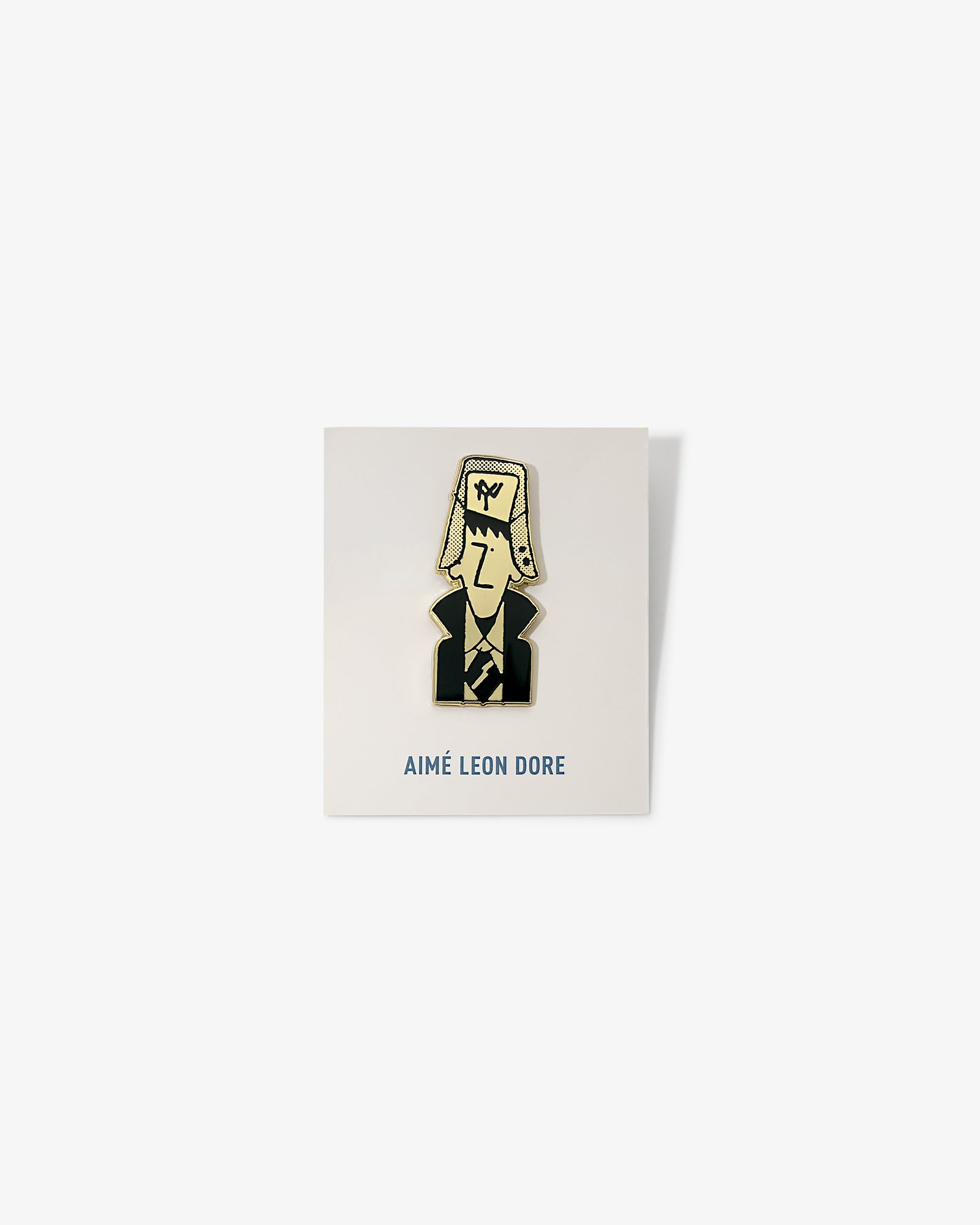 Graphic Pin featuring a cartoon man in a suit and large hat, on a white AIMÉ LEON DORE card.
