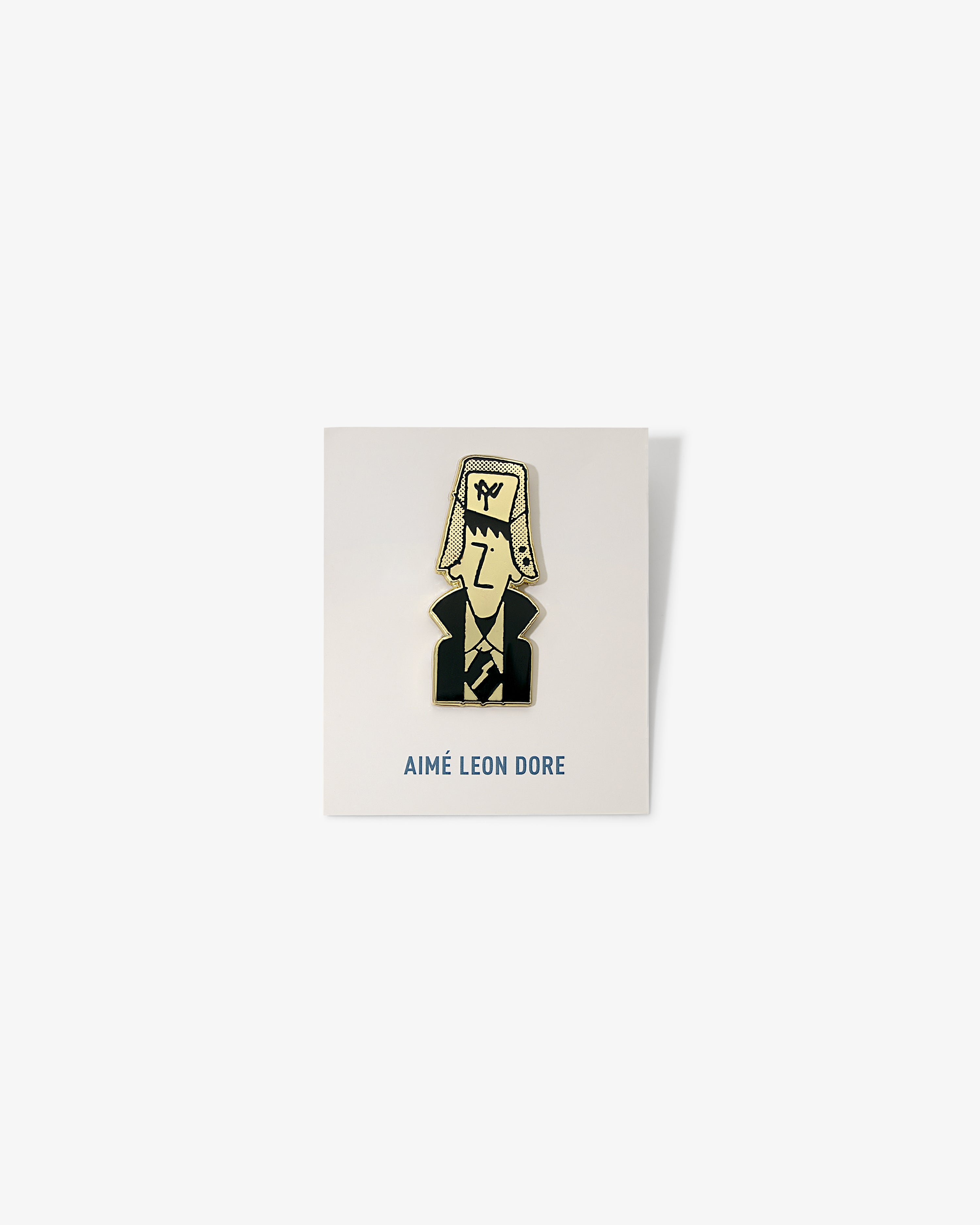 Graphic Pin featuring a cartoon man in a suit and large hat, on a white AIMÉ LEON DORE card.