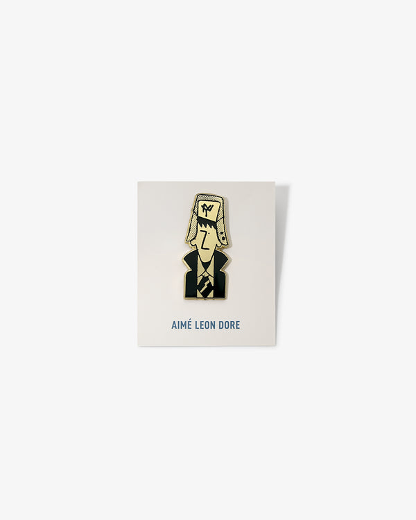 Graphic Pin featuring a cartoon man in a suit and large hat, on a white AIMÉ LEON DORE card.