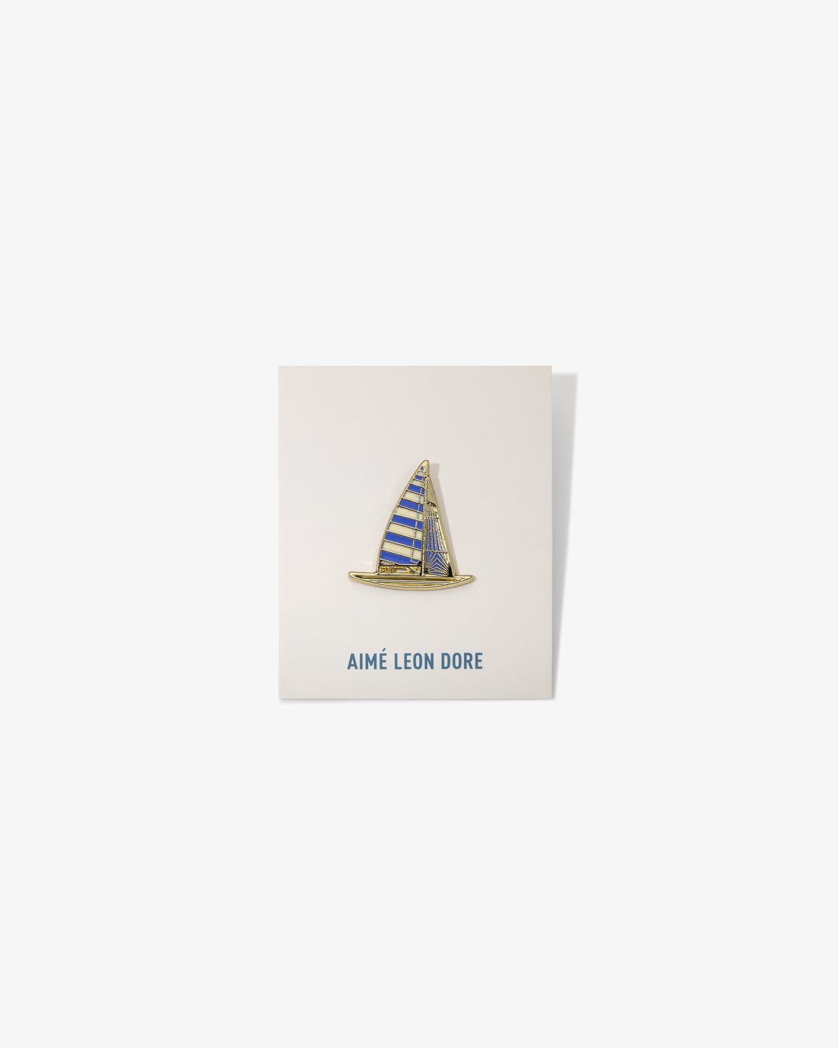 Graphic Pin featuring a sailboat with blue and yellow stripes, mounted on an AIMÉ LEON DORE card.