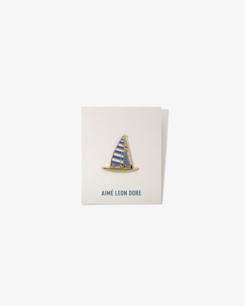 Graphic Pin featuring a sailboat with blue and yellow stripes, mounted on an AIMÉ LEON DORE card.