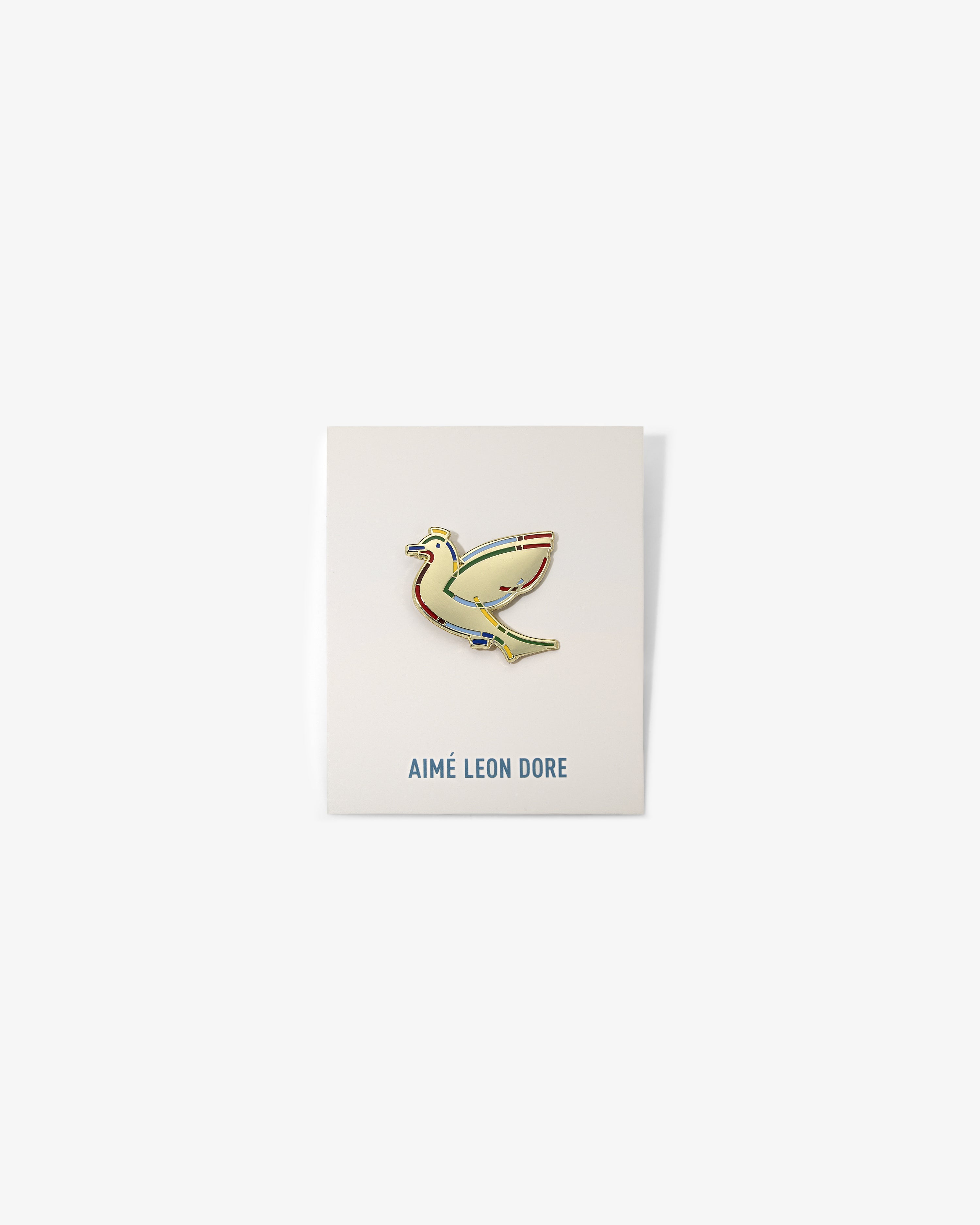 Graphic Pin featuring a yellow bird on a white card with AIMÉ LEON DORE in blue at the bottom.