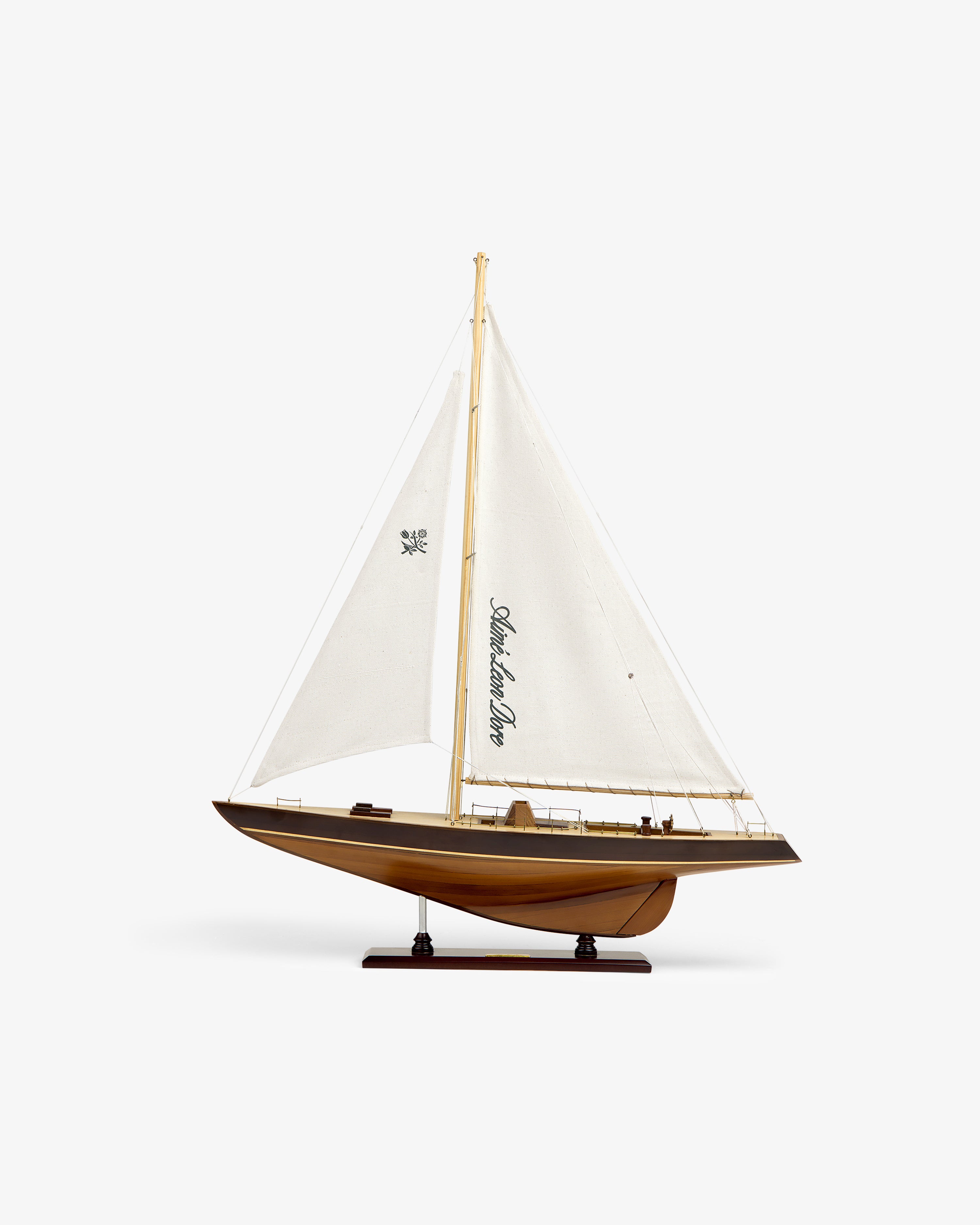 Walnut Model Sailboat featuring a white sail and wooden hull, displayed on a stand against a white background.