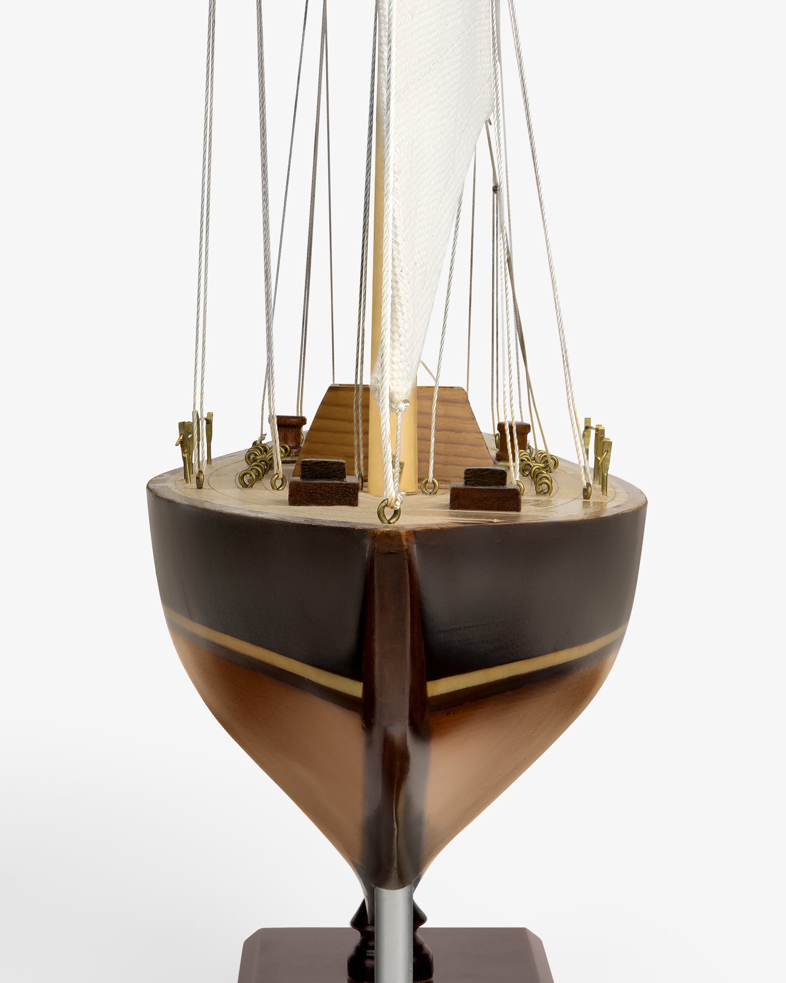 Walnut Model Sailboat seen from the front, showing brown hull, wood deck, mast, sail, and rigging on white background.