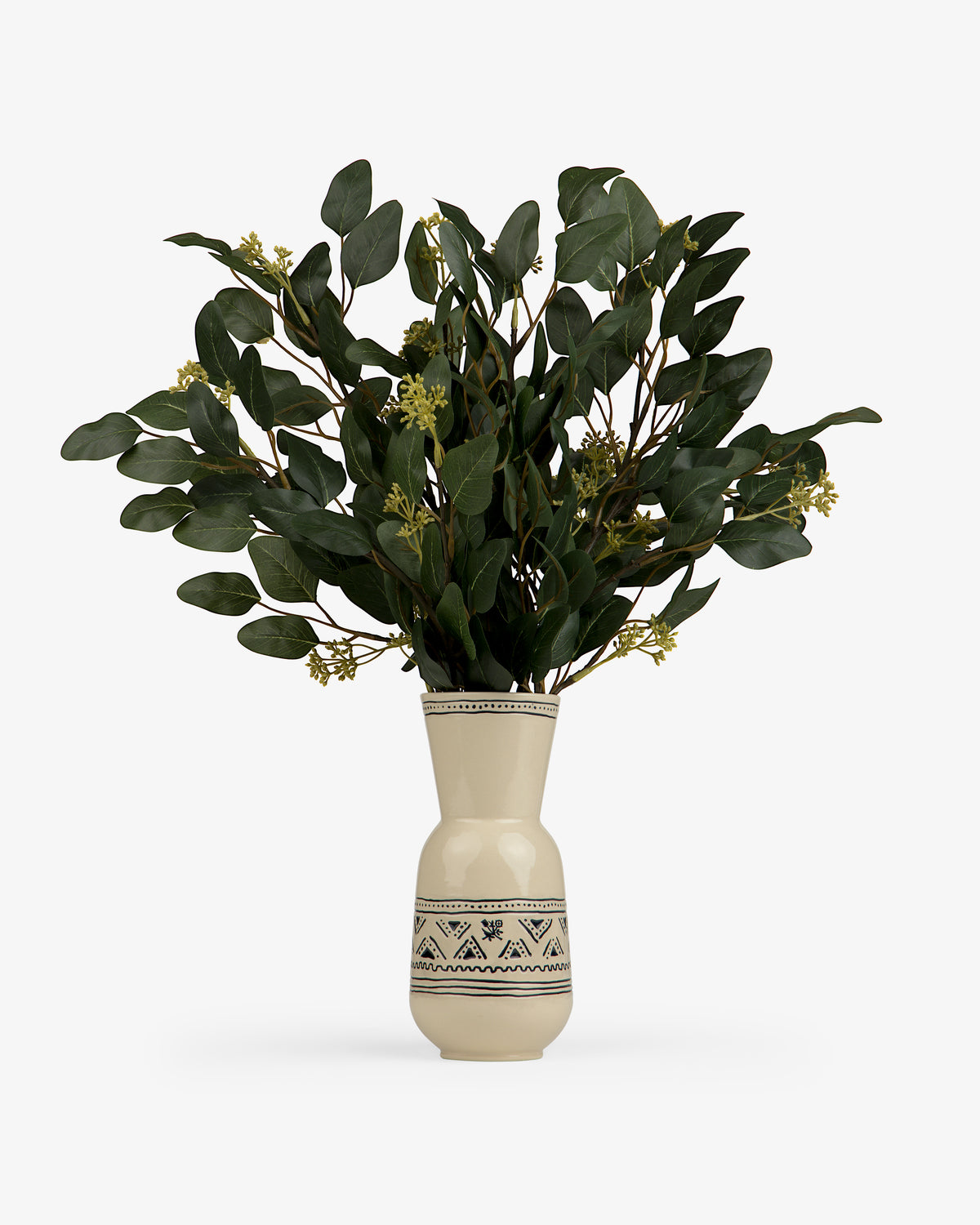 A Textile Patterned Vase holds green leafy branches with small yellow flowers.