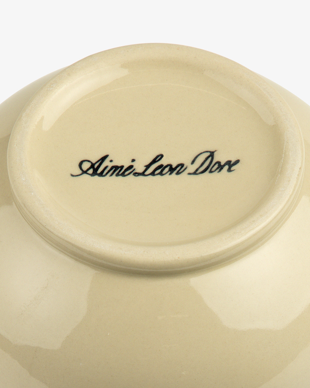 The base of a cream-colored ceramic Textile Patterned Vase with Aime Leon Dore in black script.