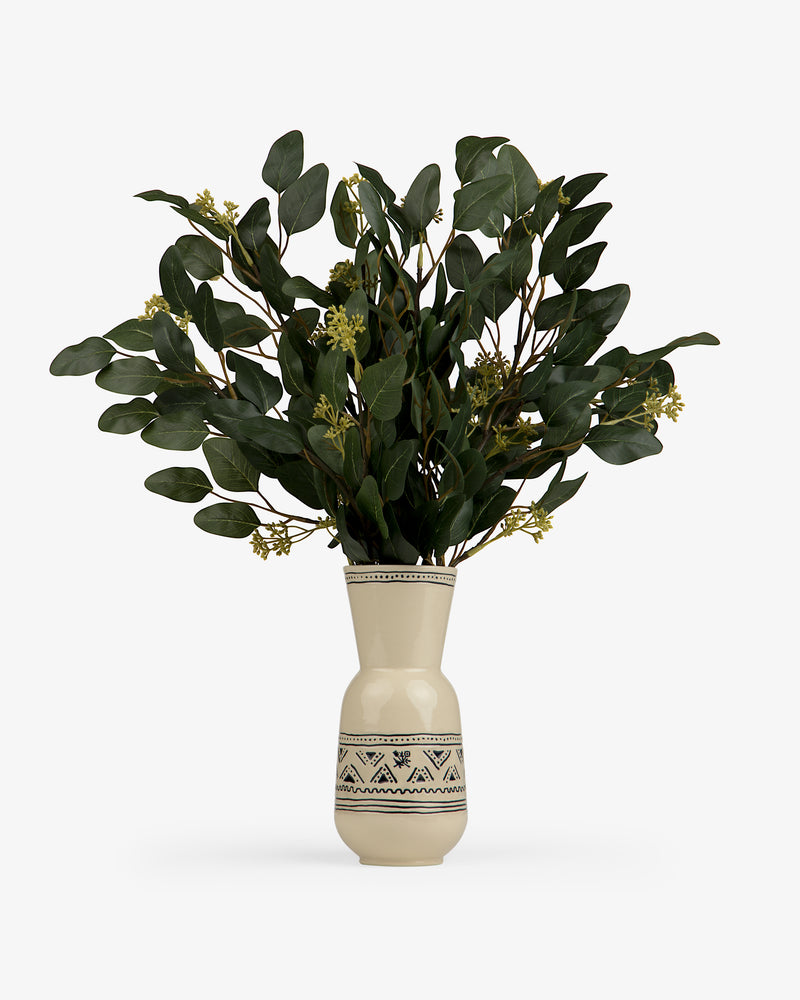 A Textile Patterned Vase holds green leafy branches with small yellow flowers.