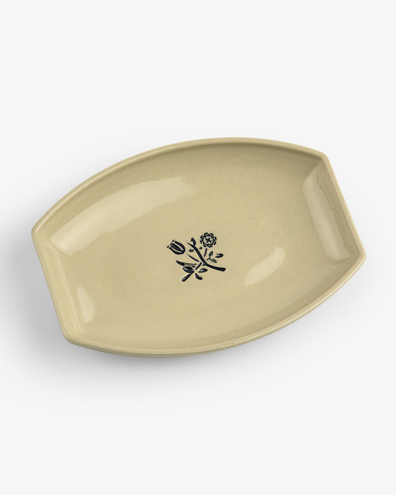 Crest Catchall: Beige, leaf-shaped ceramic dish featuring a black floral design at the center.