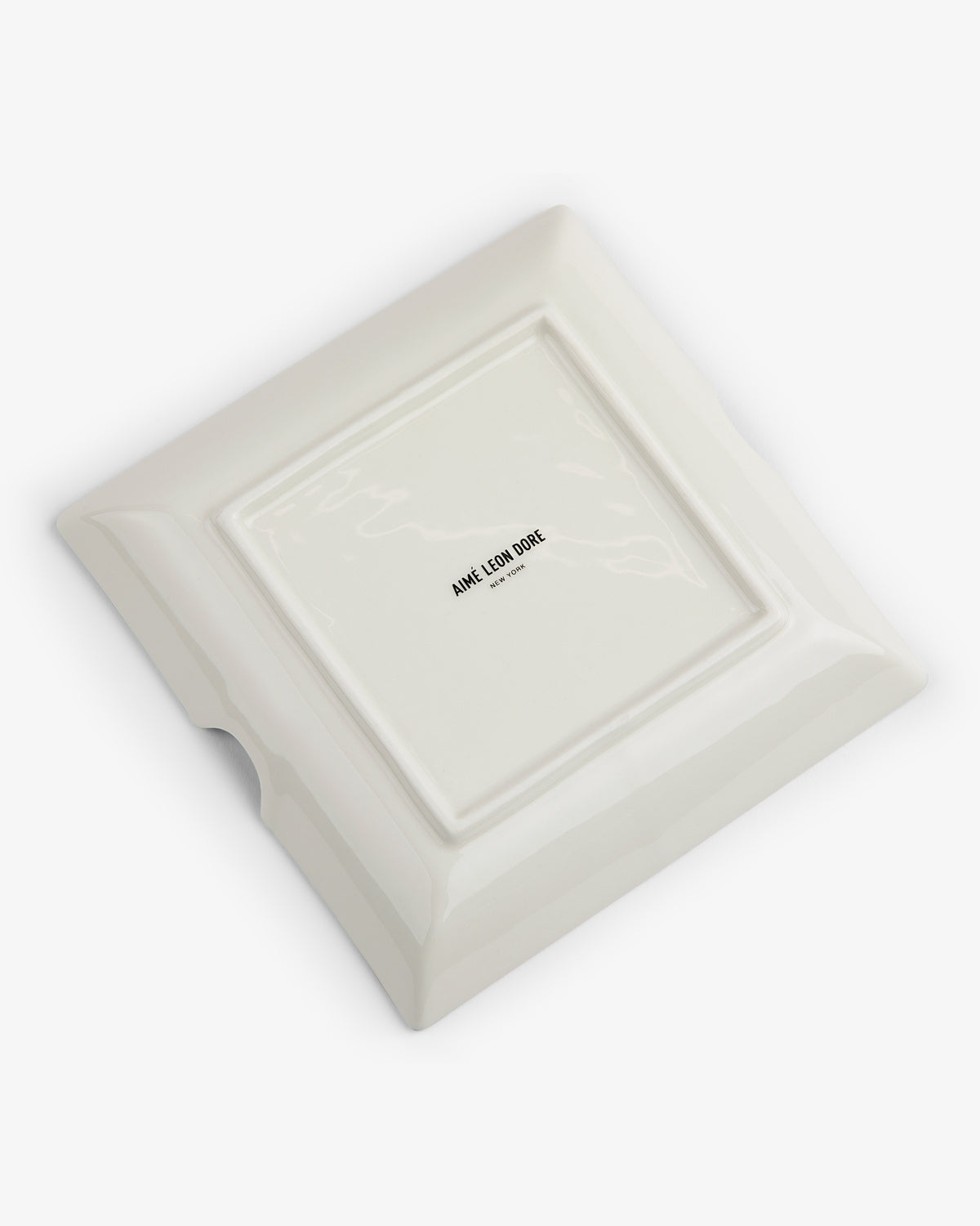 A Fassianos "Nocturnal Love" Ashtray, square and white ceramic, shown upside down with a maker's mark at the center.