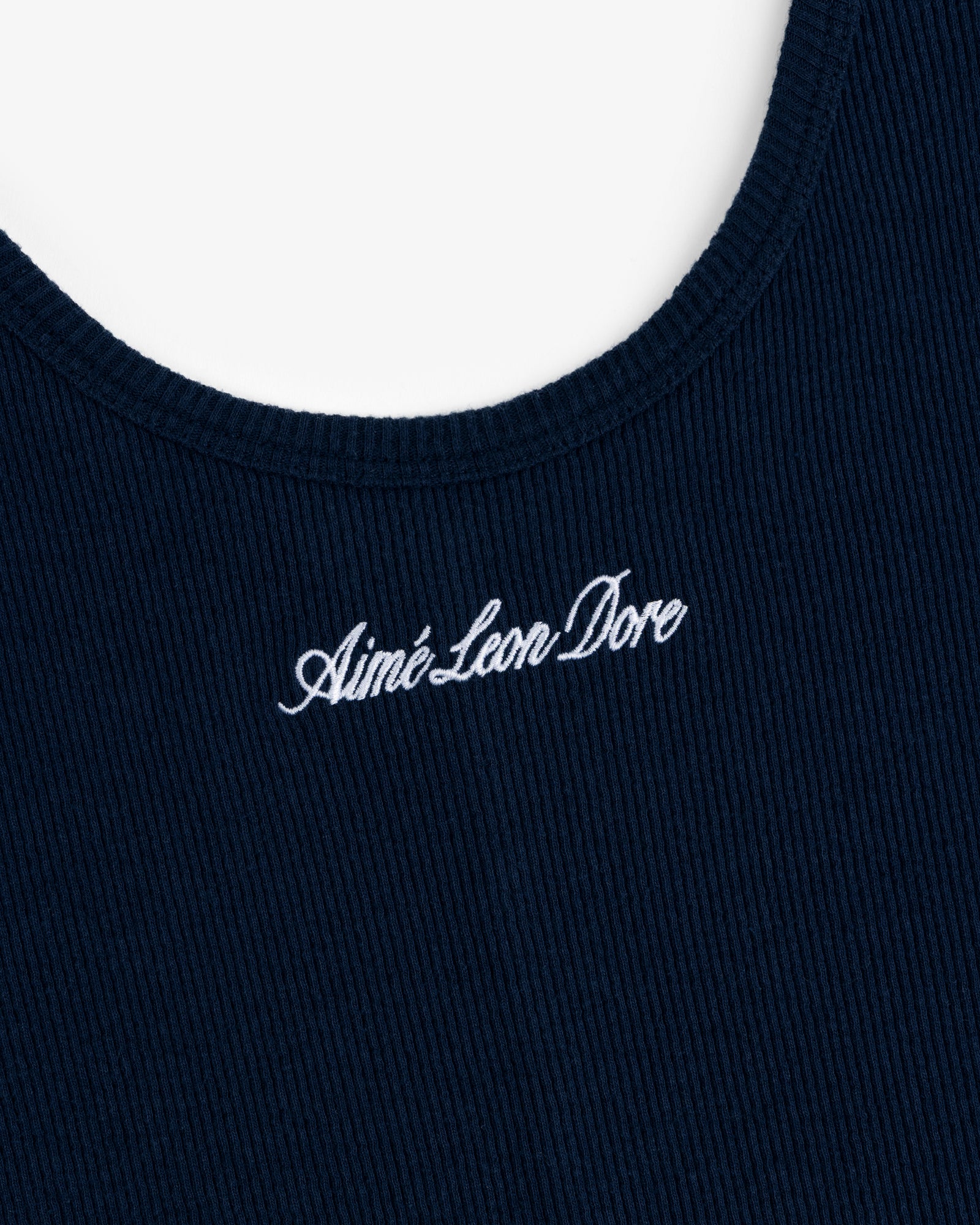 Close-up of navy ribbed fabric on the Embroidered Logo Tank Dress with white Aimé Leon Dore script near the neckline.