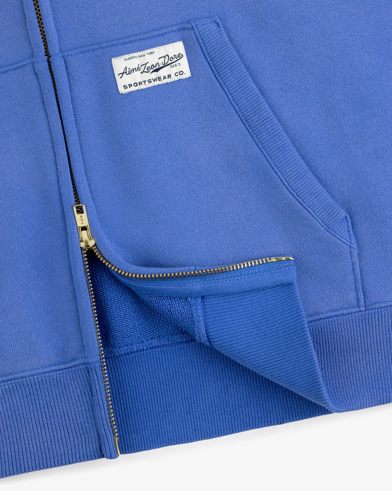 Close-up of the Sun Faded Full-Zip Hoodie in blue with gold zipper, front pockets, and white sportswear chest label.