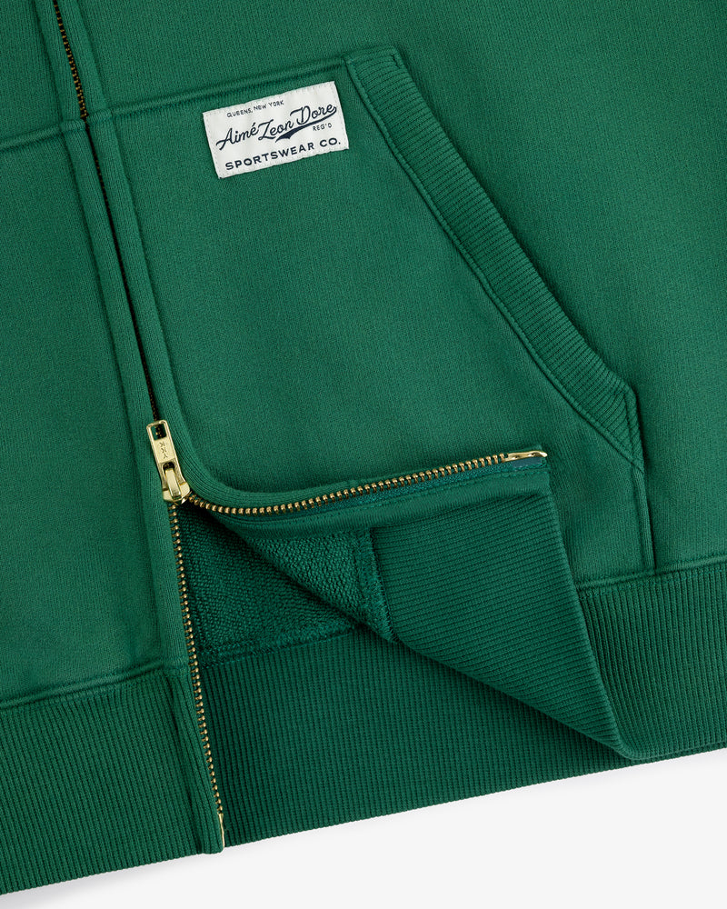 Sun Faded Full-Zip Hoodie in green with gold zippers, front pocket, and white Aimé Leon Dore Sportswear Co. label.