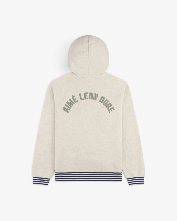 Beige Dock Hoodie with green Aimé Leon Dore text, navy striped cuffs and hem, shown from the back.