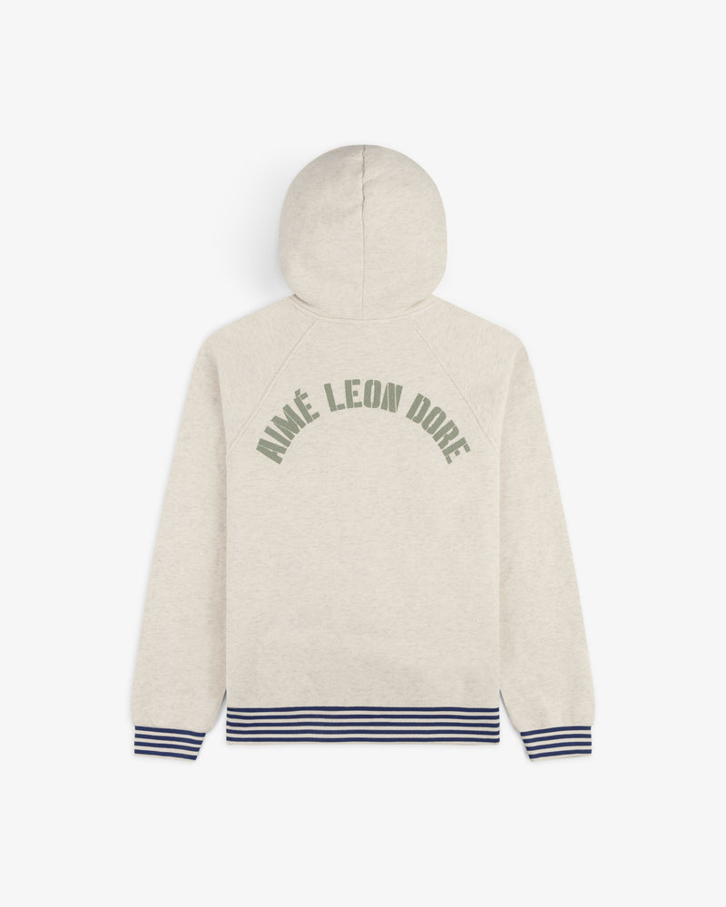 Beige Dock Hoodie with green Aimé Leon Dore text, navy striped cuffs and hem, shown from the back.