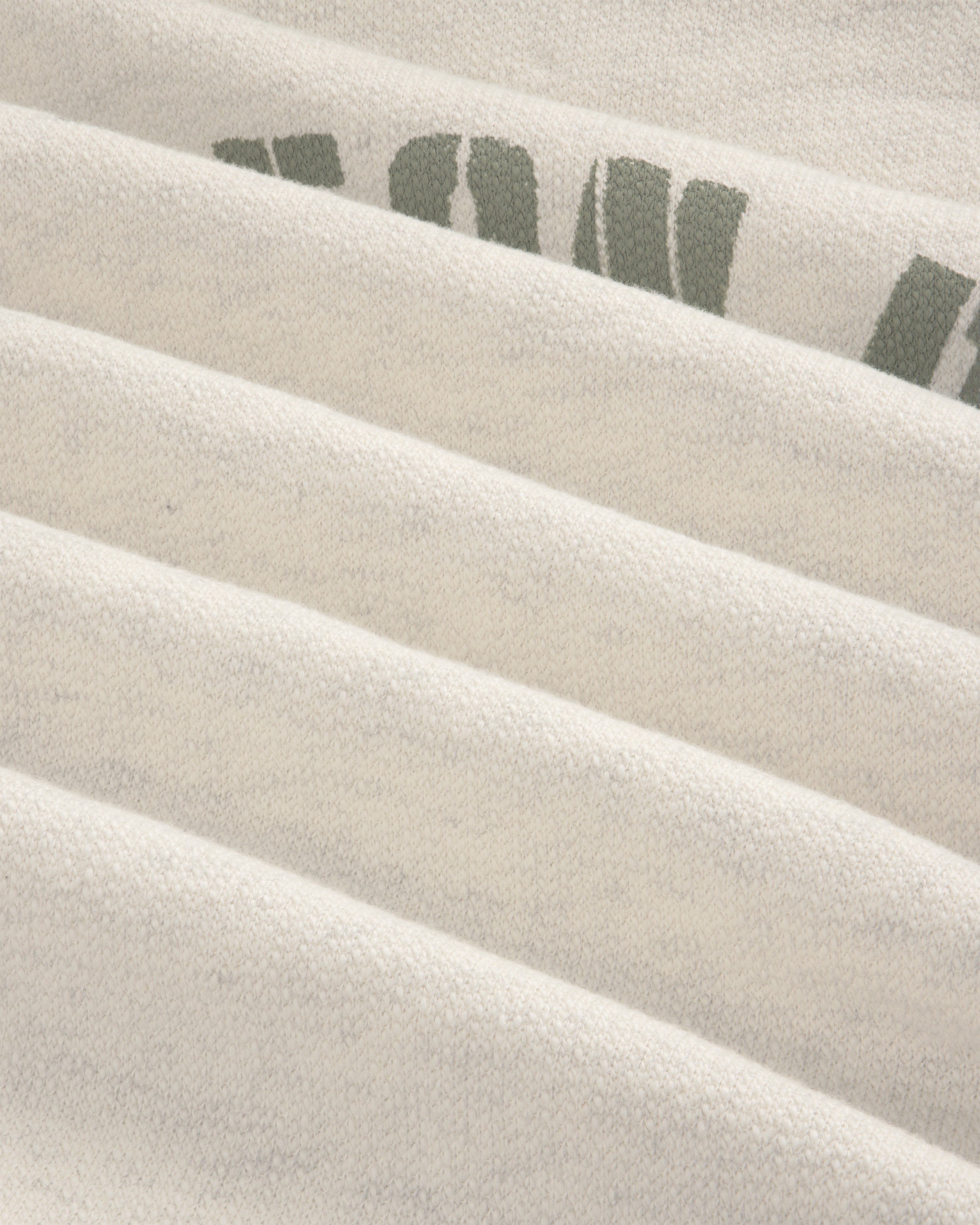 Close-up of folded Dock Hoodie in light gray with partial green letters on the top right fold.