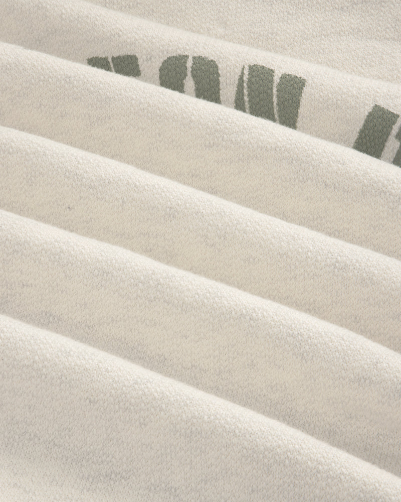 Close-up of folded Dock Hoodie in light gray with partial green letters on the top right fold.