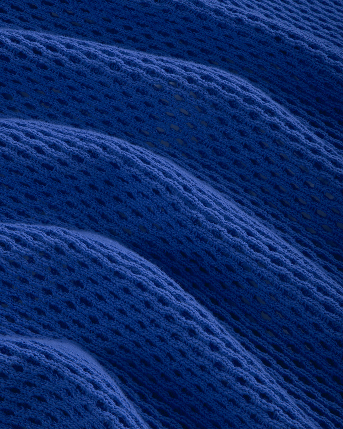 Close-up of the Open Mesh Hoodie in blue, featuring textured fabric with wavy folds and a mesh-like pattern.