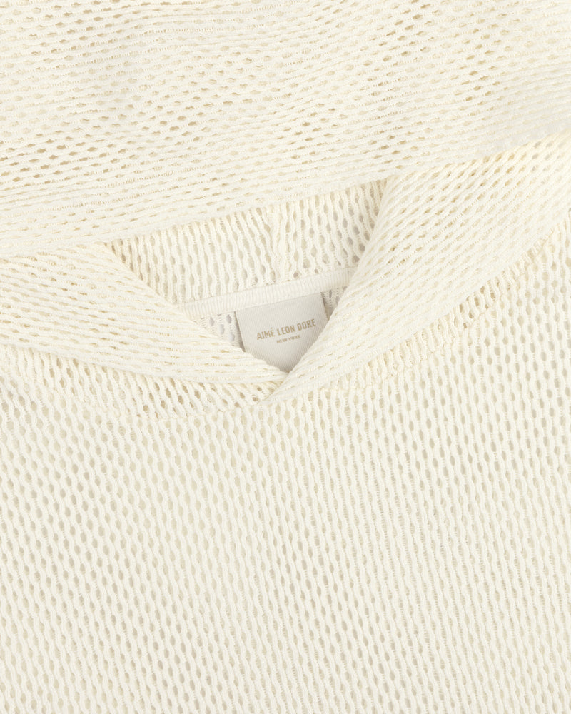 Close-up of a cream-colored open mesh hoodie with a textured knit and a visible AIMÉ LEON DORE label.