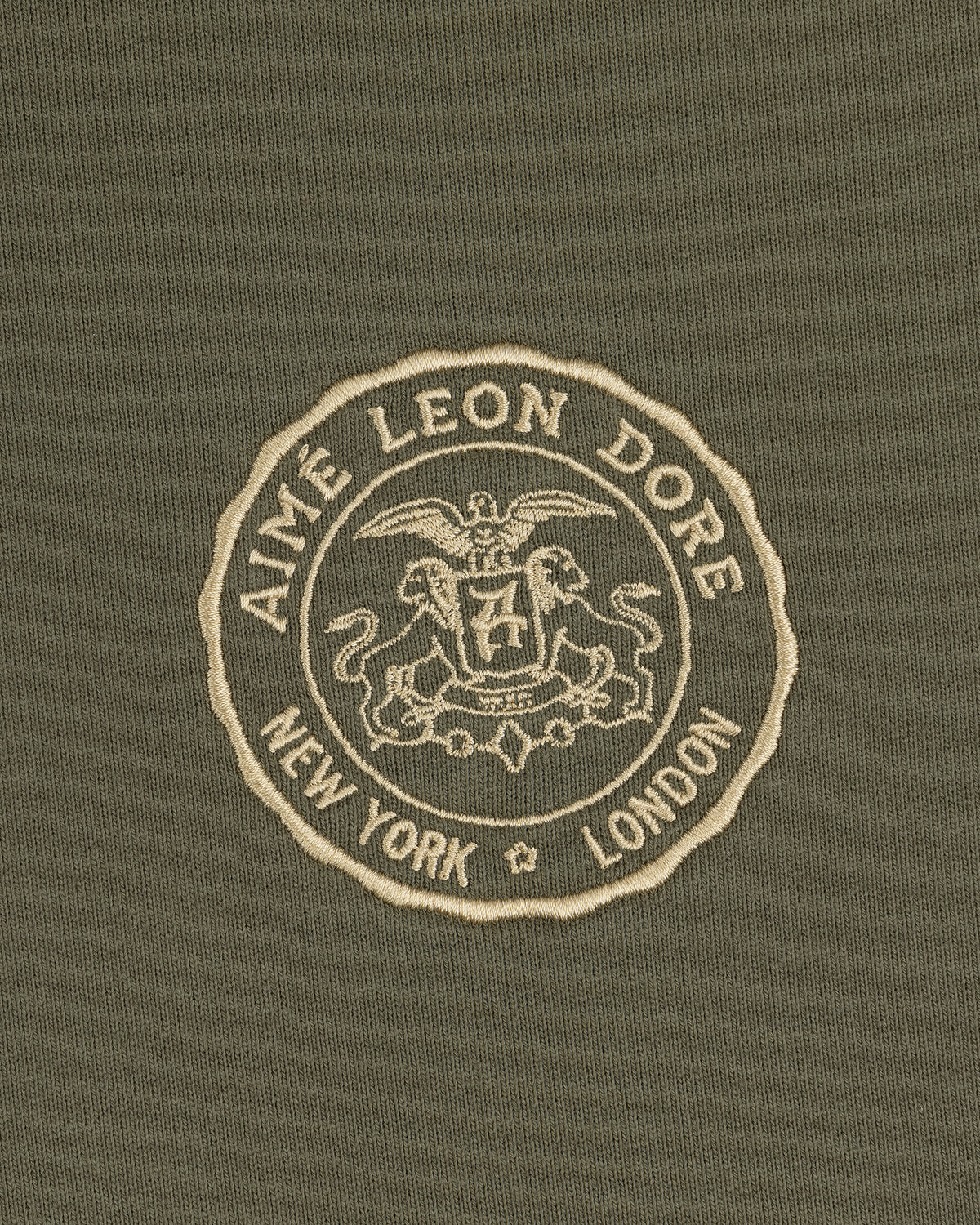 Signet Logo Hoodie featuring an embroidered Aimé Leon Dore crest with New York and London on olive green fabric.