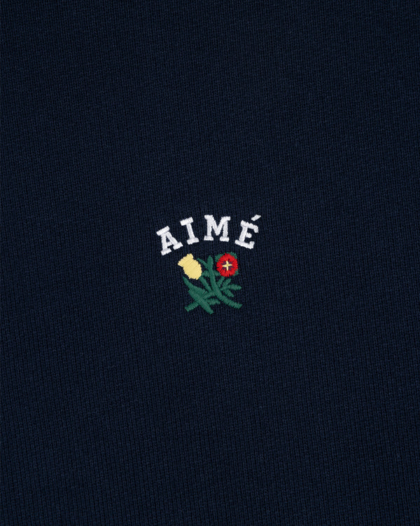 Navy Crest Hoodie with "AIMÉ" above embroidered yellow and red flowers with green stems and leaves.