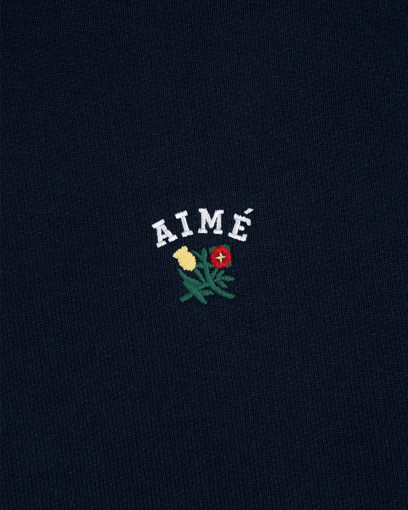 Navy Crest Hoodie with "AIMÉ" above embroidered yellow and red flowers with green stems and leaves.