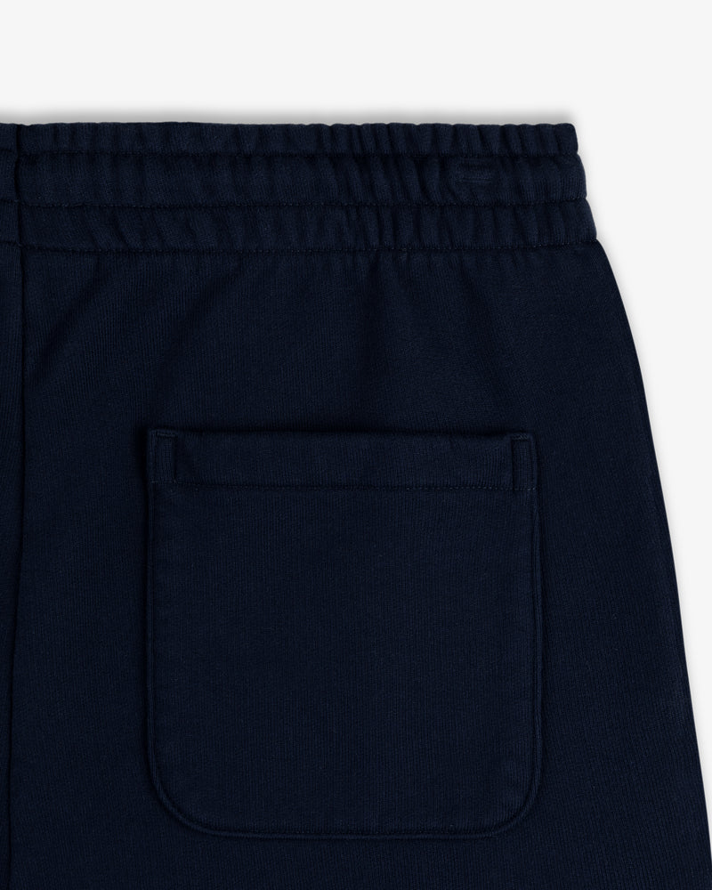 Close-up of Crest Sweatpants in navy blue with elastic waistband and one square back pocket.