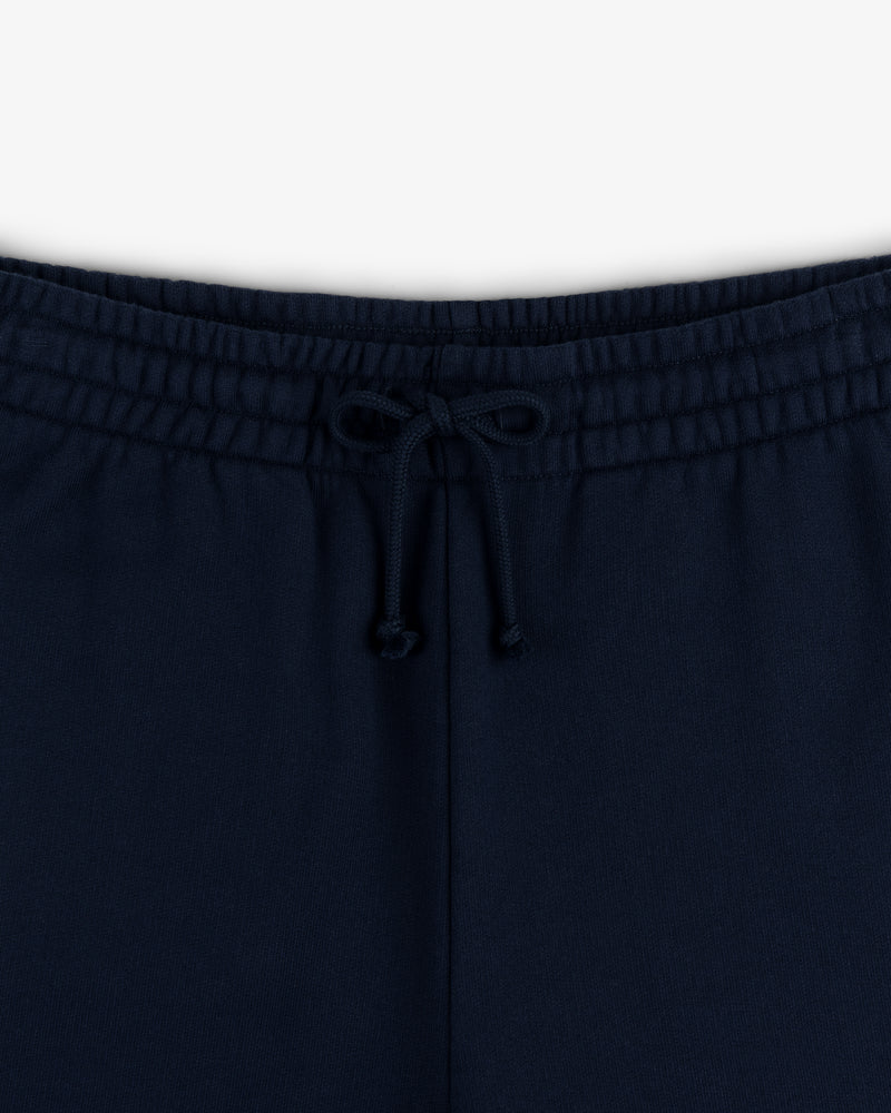 Close-up of the Crest Sweatpants waistband in navy blue, featuring a center-tied drawstring bow.