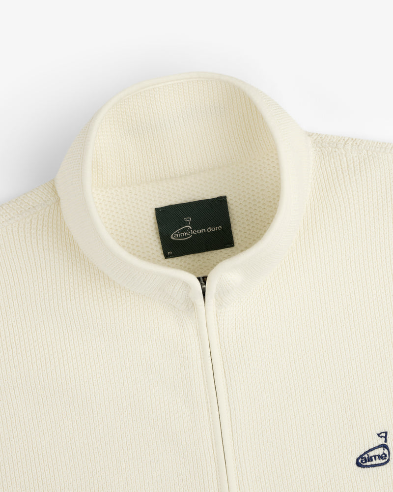 Close-up of the ALD Golf Piqué Full Zip Sweater with a ribbed texture and small navy Aimé Leon Dore chest logo.