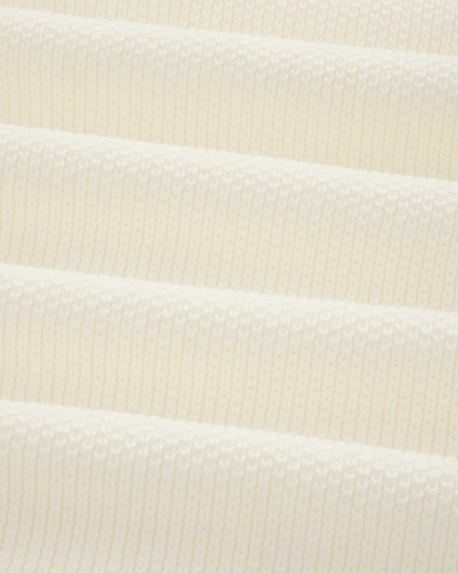 Close-up of soft, ribbed off-white ALD Golf Piqué Full Zip Sweater knit fabric in gentle horizontal folds.