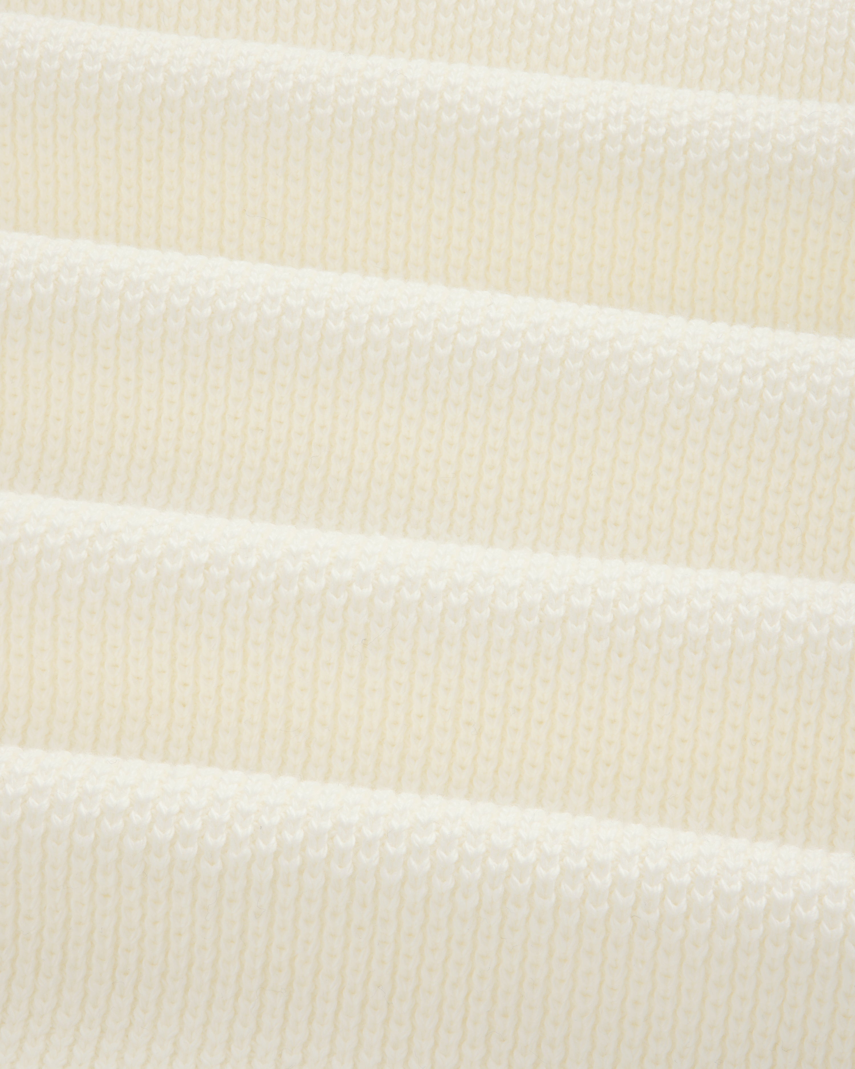 Close-up of soft, ribbed off-white ALD Golf Piqué Full Zip Sweater knit fabric in gentle horizontal folds.