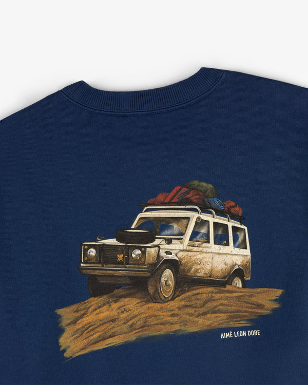 Safari Crewneck Sweatshirt featuring a loaded off-road vehicle illustration and AIMÉ LEON DORE text below the image.