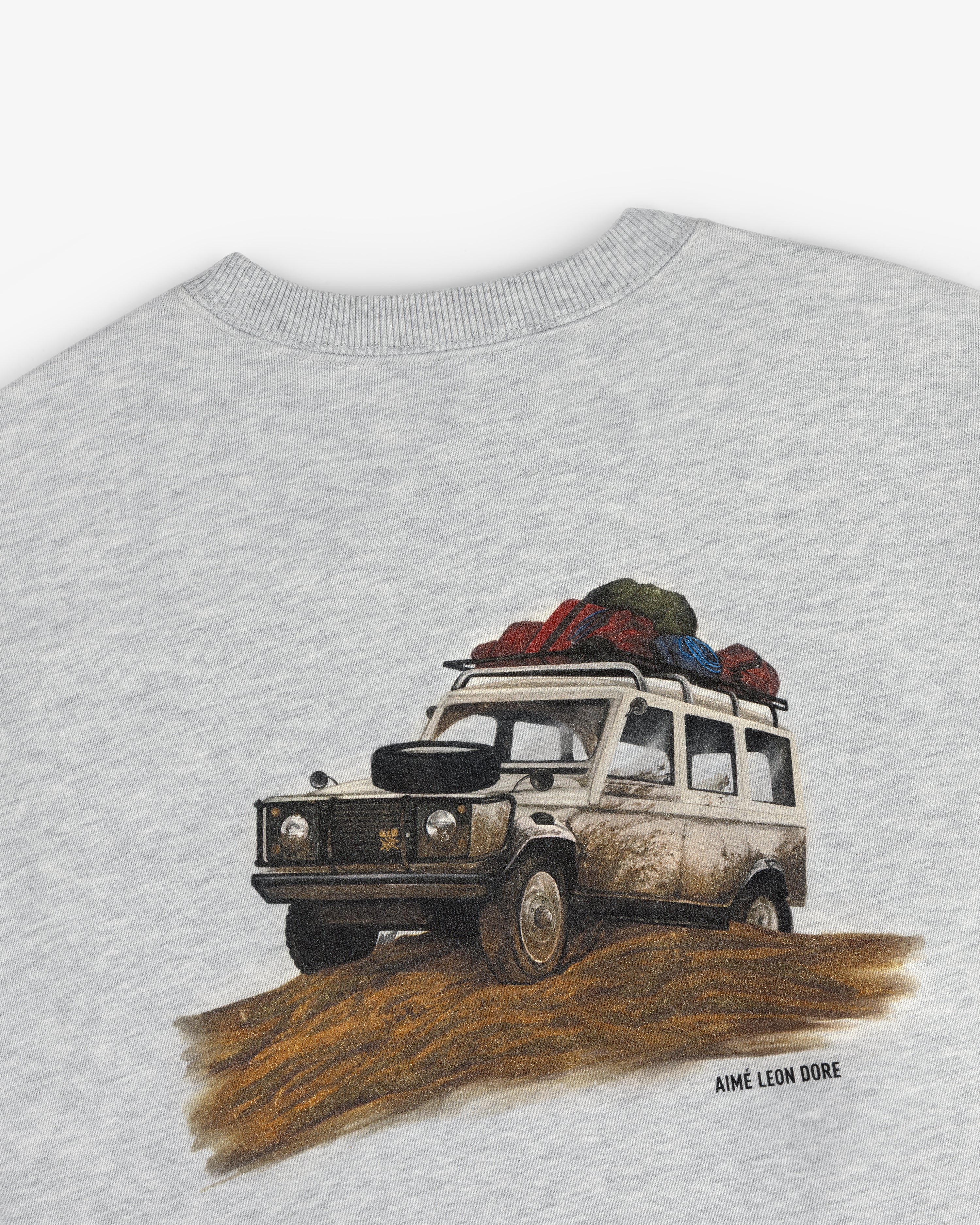 Illustration of a muddy SUV with luggage, printed on Safari Crewneck Sweatshirt with AIMÉ LEON DORE text below.