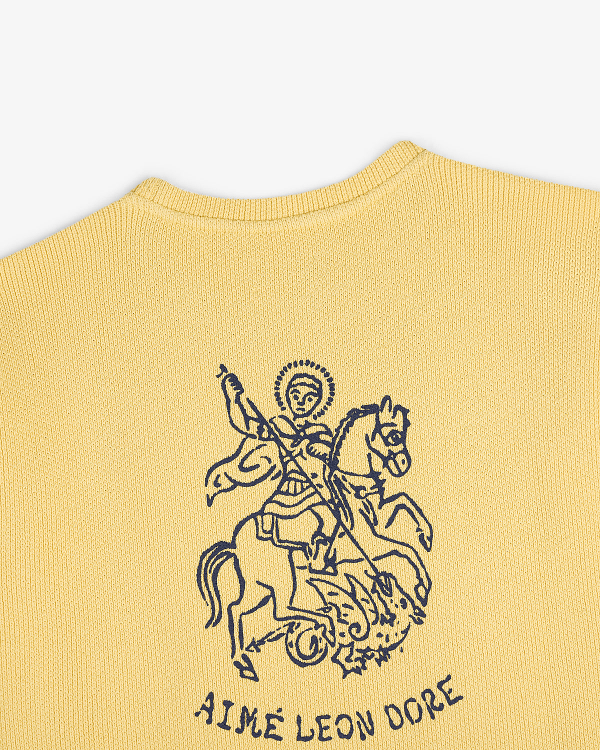 Yellow knit Saint George Piqué Crewneck with navy knight slaying dragon graphic and AIMÉ LEON DORE text below.