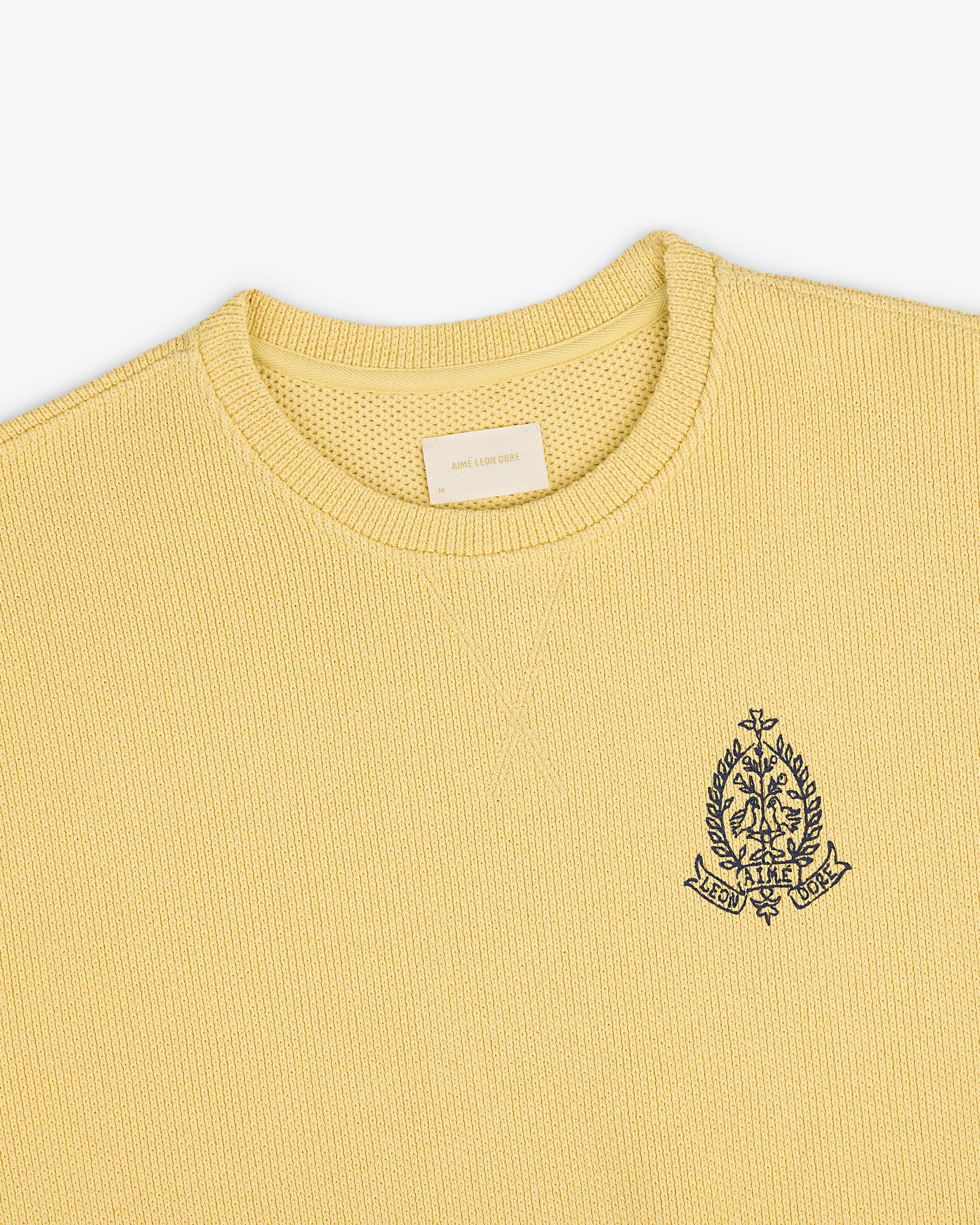 Saint George Piqué Crewneck Sweatshirt in yellow with a navy crest on the left chest and beige collar tag.