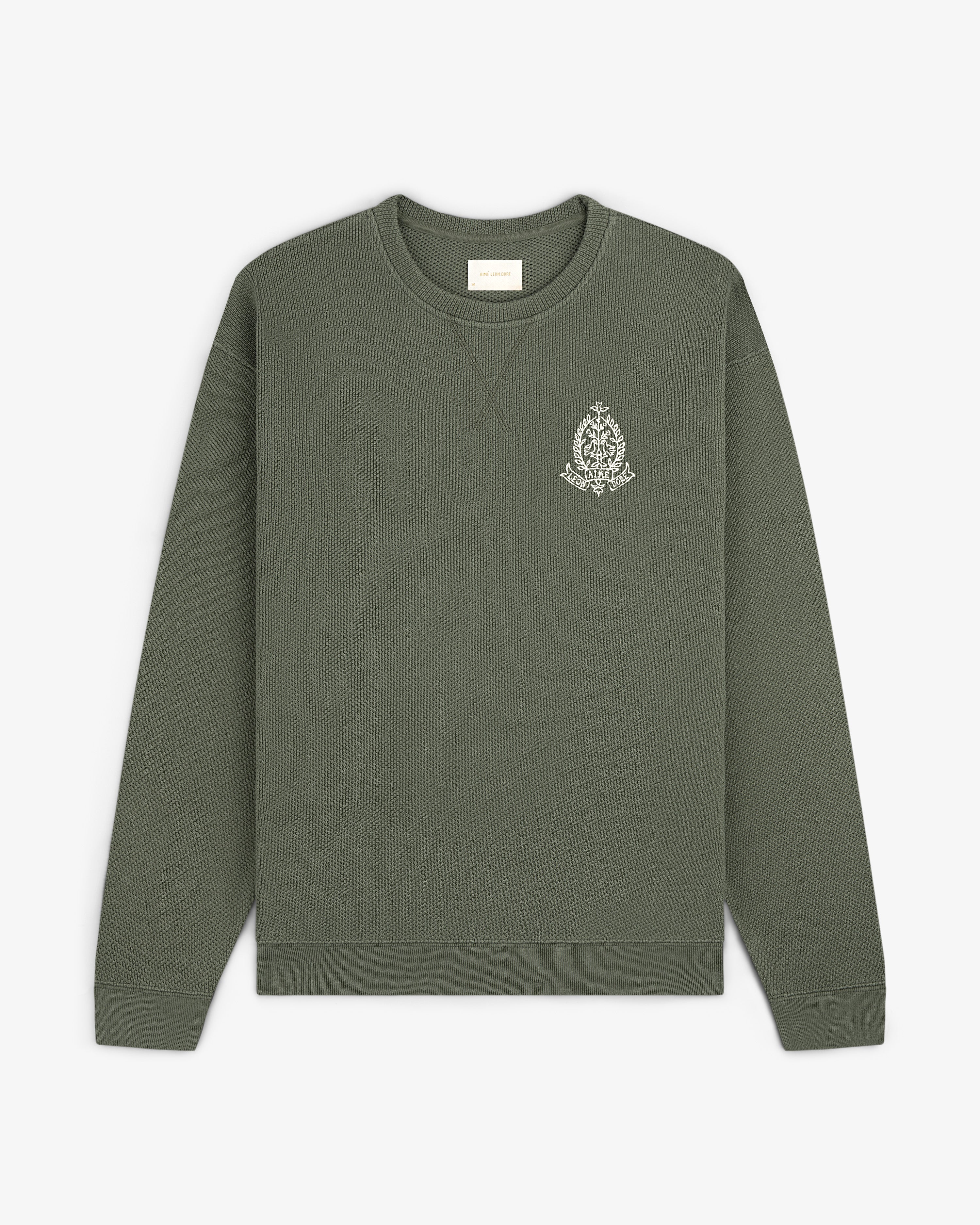 Saint George Piqué Crewneck Sweatshirt in olive green with a small white logo on the left chest, laid flat.