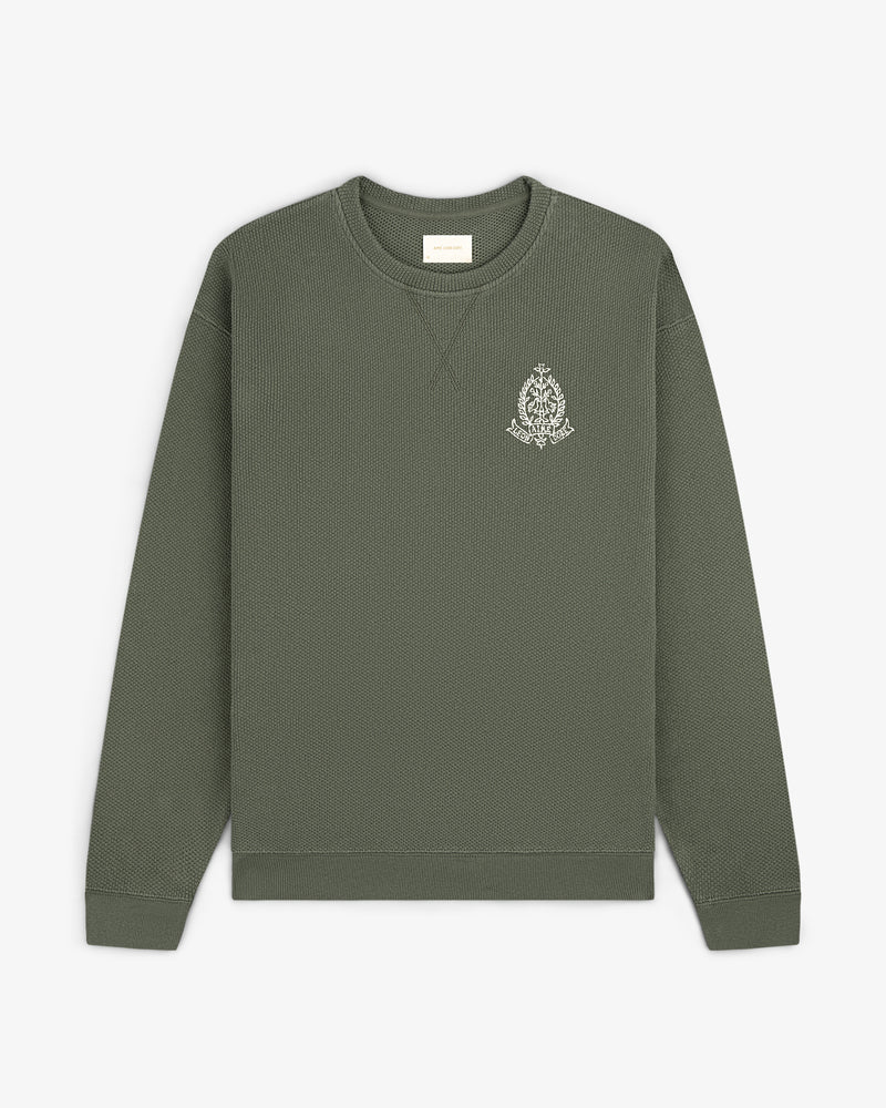 Saint George Piqué Crewneck Sweatshirt in olive green with a small white logo on the left chest, laid flat.